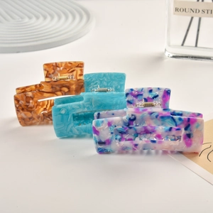 Close-up of three colorful large acetate claw clips in marble and cloud patterns