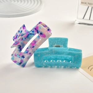 Detail of square acetate hair claw clips in blue marble and floral patterns with metal spring