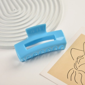 Macro shot of glossy blue acetate rectangular hair claw clip for elegant hairstyles
