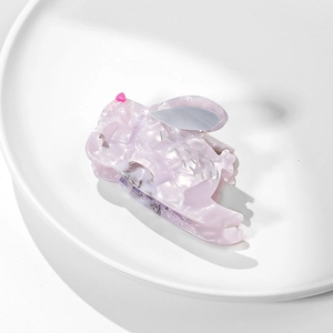Close-up of pink marble acetate rabbit hair claw clip on a minimalist ceramic tray