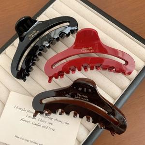Three acetate hair claws in red, black, and amber on a velvet tray for women