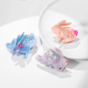 Cute acetate rabbit claw clips in marble blue, pink, and purple on a white plate
