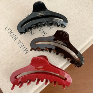Three elegant French acetate hair claws in black, brown, and red colors with gold logos