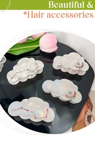 Macro shot of four pearlescent cloud hair clips with colorful rhinestones and moon motifs
