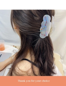 Detailed view of white pearlescent acetate hair claw clip with colorful rhinestones