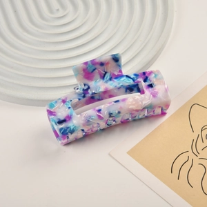 Detail view of large marble-patterned acetate hair claw clip on minimalist decor
