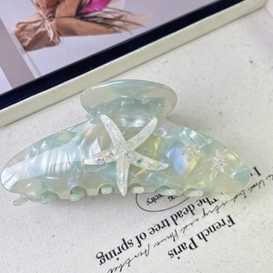 Close-up of mint green acetate hair claw clip with glitter starfish and shell texture