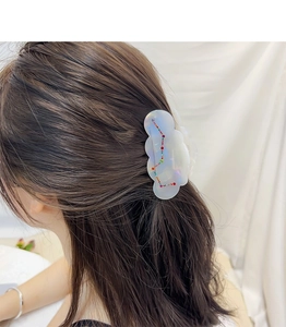 Detail of pearlescent acetate hair claw with cloud edges and colorful rhinestones on hair