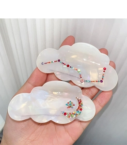 Detailed macro view of pearlescent white acetate cloud hair claws with rhinestone patterns