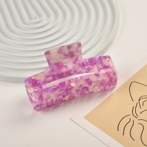 Close-up of a rectangular purple marble acetate hair claw clip on a white display tray