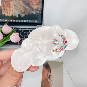 Detail view of pearl white cloud hair claw clip with colorful moon and star rhinestones
