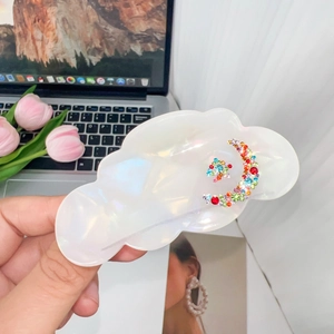 Detailed shot of pearlescent cloud hair claw with colorful moon and star rhinestones