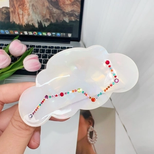 Macro detail of cloud-shaped acetate hair claw with iridescent pearls and colorful rhinestones
