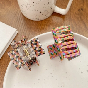 Checkered pattern large hair claw clips in colorful and neutral tones displayed on a ceramic tray