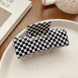 Close-up of black and white checkerboard square hair claw clip with glossy acetate texture