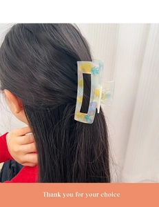 Pince à cheveux rectangulaire vert clair à imprimé ananas portée sur de longs cheveux noirs