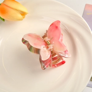 Détail de la pince à cheveux papillon en acétate marbré rose avec ressort doré élégant