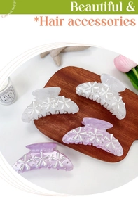 Close-up of pearl flower hair claw clips in white and purple on a wooden tray