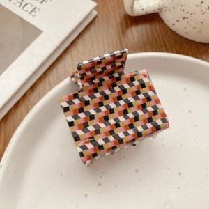 Detail of colorful checkered acetate hair claw clips displayed on a minimalist tray