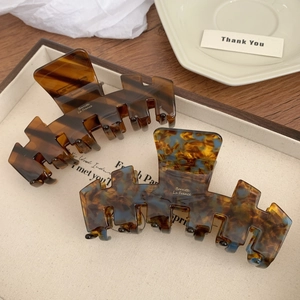 Set of large acetate hair claws in tortoise shell and blue-yellow marble on a cream tray