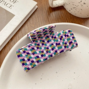 Detailed close-up of a multicolor geometric checkered claw clip on a white ceramic tray