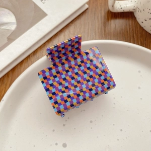Detail of a medium square checkerboard hair claw clip in colorful acetate on a ceramic tray