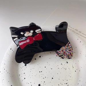 Détail de la pince à cheveux chat noir avec nœud rouge et paillettes arc-en-ciel