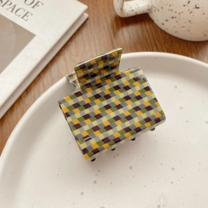 Detailed view of green and yellow checkerboard hair claw clip on a ceramic tray