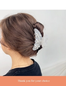 Close-up of a large pearlescent floral hair claw clip securing a French bun hairstyle