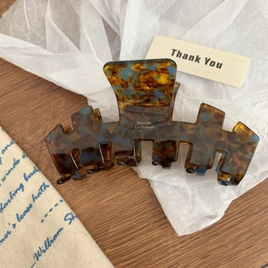Close-up of a large tortoiseshell acetate hair claw clip with polished surface on fabric