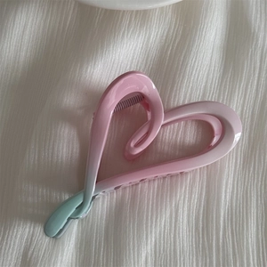 Detailed view of heart-shaped hair claw clip with pink to mint green gradient finish