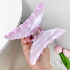 Close-up of a purple marble butterfly hair claw clip being held to show its large size