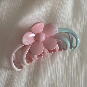 Pink and blue gradient hair claw clip with floral 3D accents on white textured surface