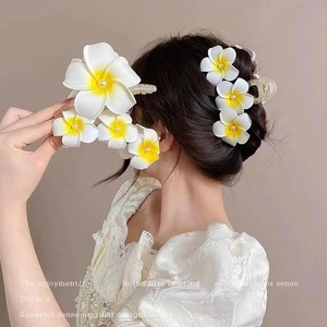 Détail des pinces à cheveux frangipane avec dégradé jaune et perles sur le modèle