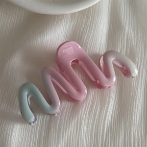 Elegant wavy hair claw clip with pink to mint green gradient on white fabric