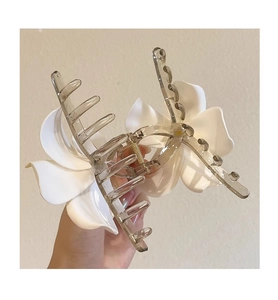 Détail d'une pince à cheveux florale avec fleurs de frangipanier et finition gris fumé