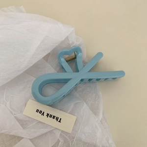 Détail de la pince à cheveux bleu clair en forme de cœur avec design croisé sur papier