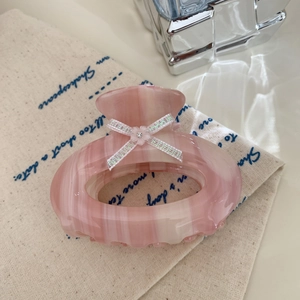 Macro view of pink marble acetate hair claw clip featuring a glittery bow and rhinestone
