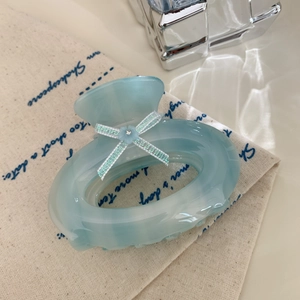Detail of light blue acetate hair claw clip with glitter bow and small floral accent