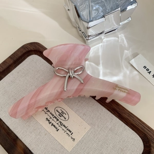 Détail de la pince à cheveux en acétate marbré rose avec nœud argenté et gravure