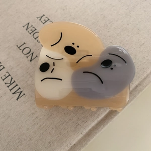 Detail view of acetate claw clip with three cartoon dogs on a book background