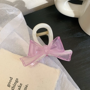 Detailed view of cream white hair claw clip with a textured pink mesh bow and metal spring