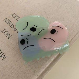Close-up of a cartoon acetate hair claw clip with colorful pastel shapes on a book