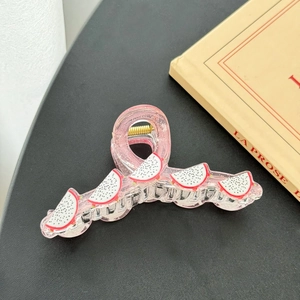 Detail view of pink resin hair claw clip with pitaya fruit patterns and gold spring
