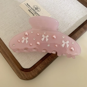 Detail of pink acetate flower hair claw clip with rhinestones and bow decoration