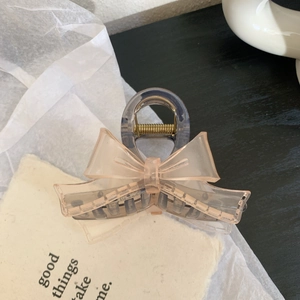 Detail view of pink bow hair claw clip with semi-transparent finish and metal spring