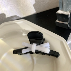 Vue détaillée d'une pince à cheveux panda noire avec nœud blanc et ressort en métal