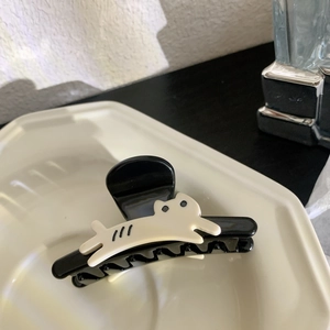 Détail d'une pince à cheveux panda mignonne en résine noire posée sur une assiette blanche
