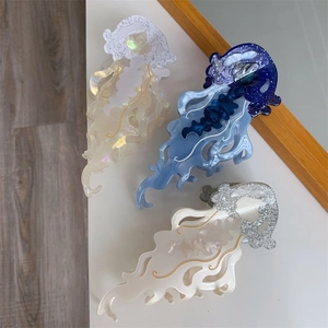 Three jellyfish-shaped acetate hair claws in iridescent white, blue, and cream colors
