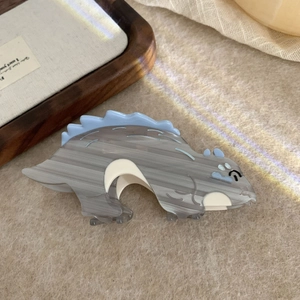 Detailed view of dinosaur hair claw made of marble gray acetate with blue fins